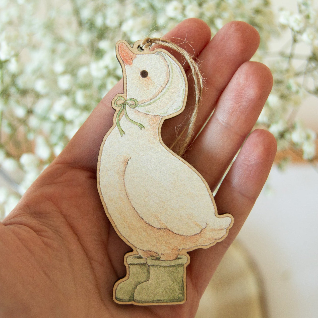 Rainy Duck wooden hanging decoration by Beccotti shown for scale in hand.